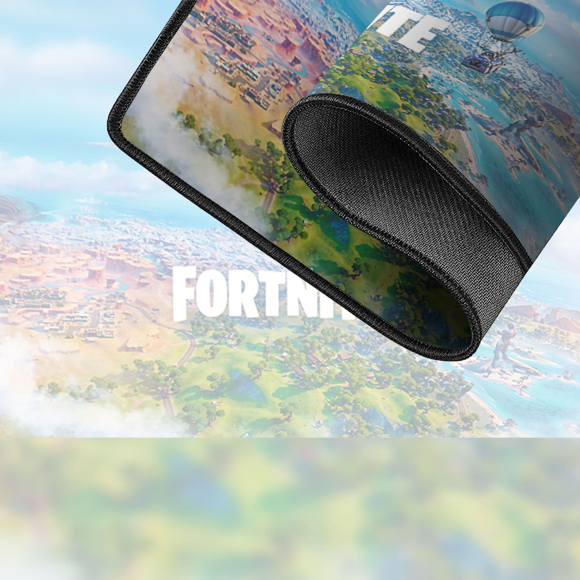 Un tapis de souris de jeu XXL enroulé présentant une vue aérienne colorée de l'île Fortnite, avec le logo FORTNITE blanc partiellement visible en arrière-plan, parfait pour tout fan de Tapis de souris Fortnite.